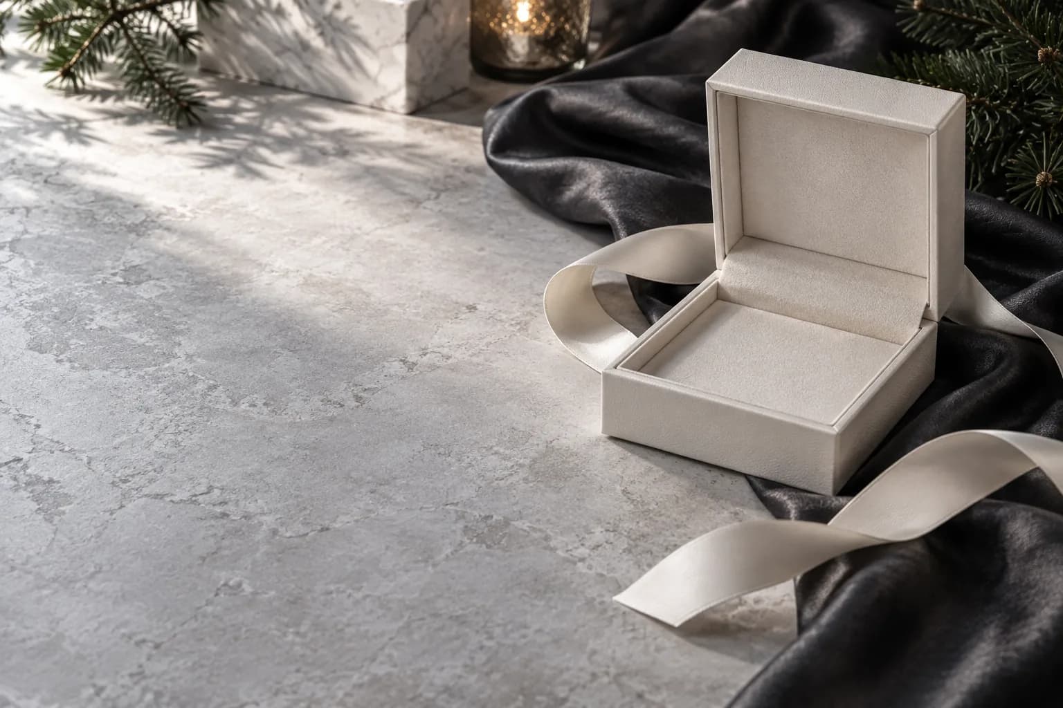 Écrin vide et ruban ivoire sur soie graphite avec ombres de sapin